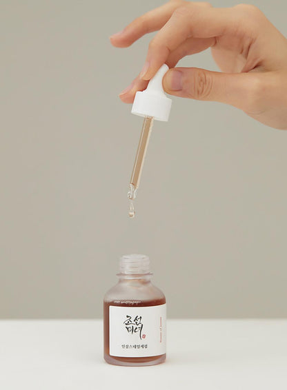 A hand squeezing the pipette dropper of Beauty Of Joseon Revive Serum 