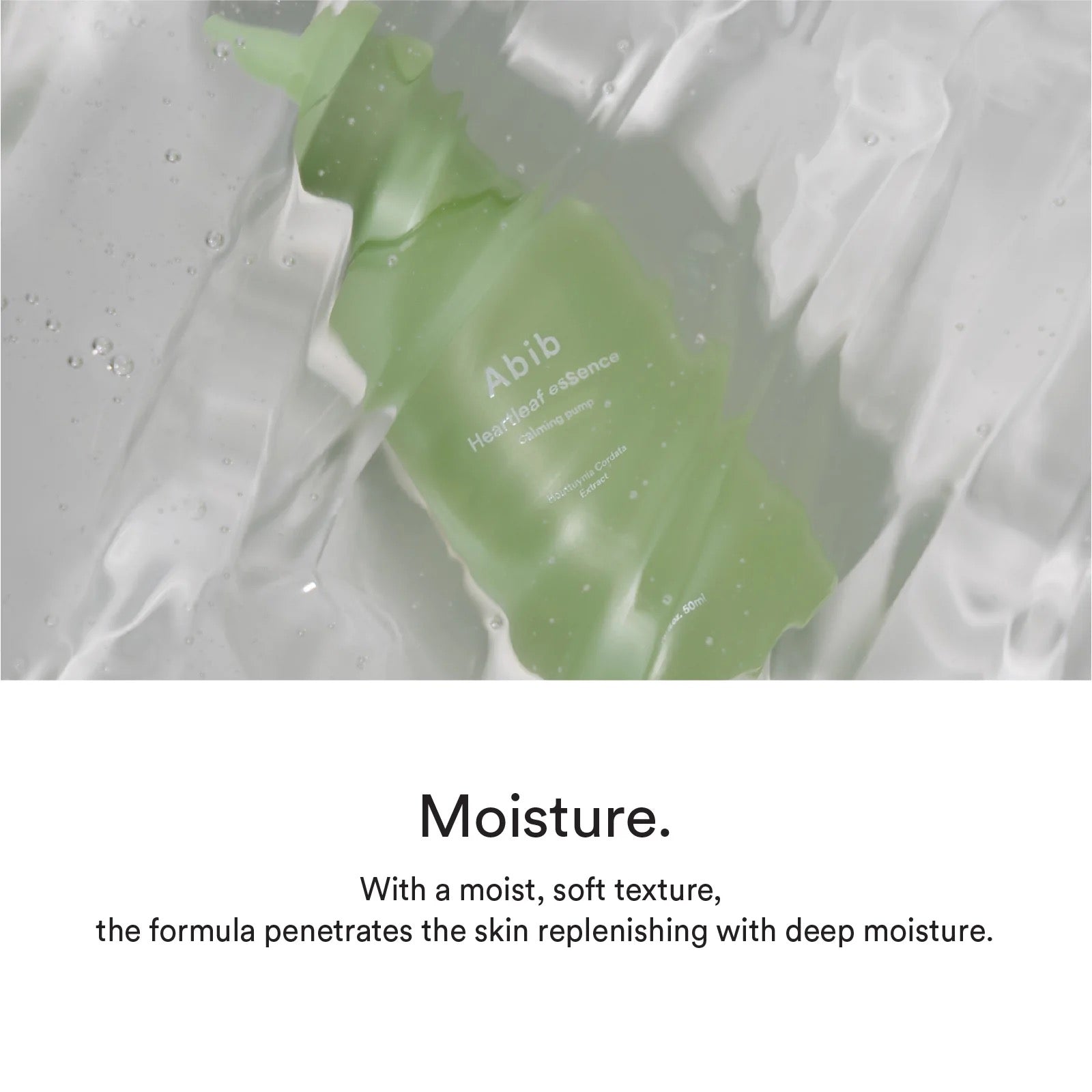 A green bottle under a water-like effect  of an Abib Heartleaf essence calming pump, with Houttuynia cordata extract