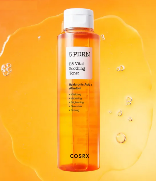 A bottle of COSRX 5 PDRN B5 Vital Soothing Toner filled with orange liquid, set against a vibrant orange background with a liquid splash and bubble details.