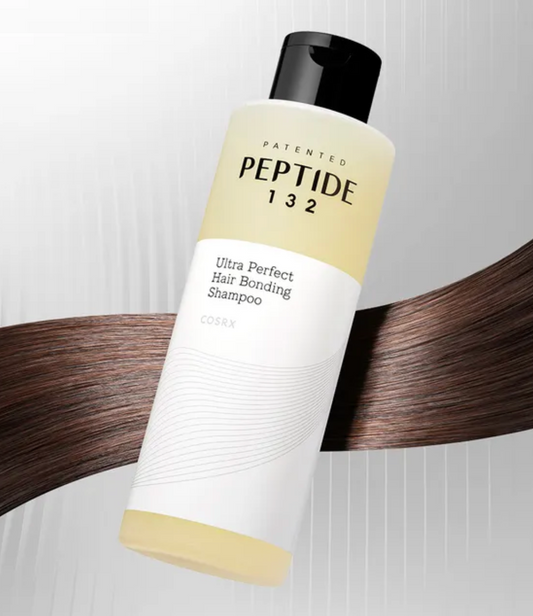 A bottle of COSRX Peptide 132 Ultra Perfect Hair Bonding Shampoo floating over a curved strip of dark brown hair.