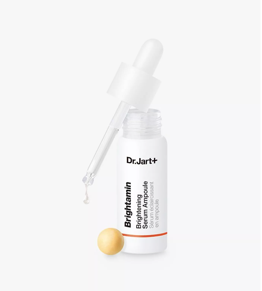 Dr. Jart+ Brightening Serum Ampoule in a white bottle with a glass dropper, shown on a clean white background with a small gold ampoule ball beside it.