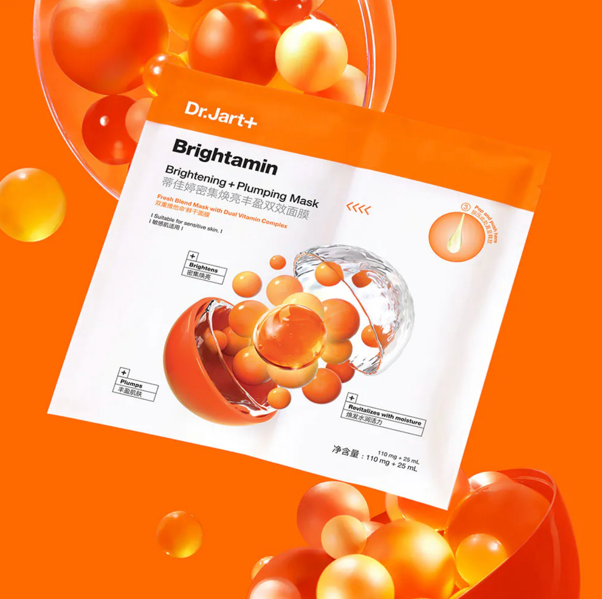 A sheet mask package labeled Dr.Jart+ Brightamin Brightening + Plumping Mask, shown at an angle on a vivid orange background with floating orange and amber gel spheres and glass bowl elements.