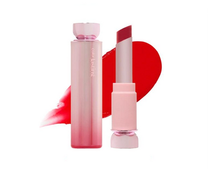 A cosmetic lipstick bottle and matching lipstick bullet shown on a white background, with a red lipstick smear behind them. The bottle and cap are pale pink, and the lipstick bullet is a deeper rosy red.