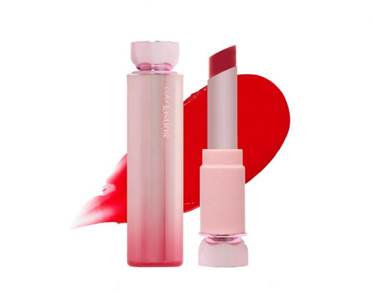 A cosmetic lipstick bottle and matching lipstick bullet shown on a white background, with a red lipstick smear behind them. The bottle and cap are pale pink, and the lipstick bullet is a deeper rosy red.