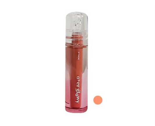 A clear cylindrical cosmetic bottle with a transparent cap, filled with a pink-to-rose gradient liquid. A plain white background with a small peach swatch circle to the right.