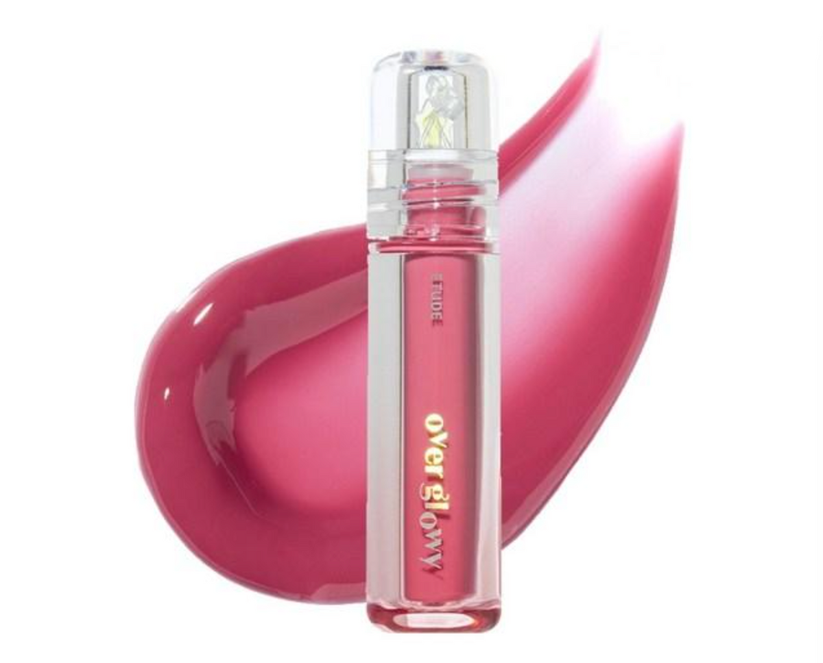 A clear cylindrical tube of lip color with pink liquid inside, shown in front of a glossy pink color smear on a white background.