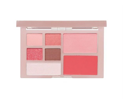 A makeup palette in a pale pink case, shown open against a plain white background. The shades include light pink, shimmering coral pink, a matte dusty rose, a deep glittery pink-red, a warm brown, and a bright coral-red cream.