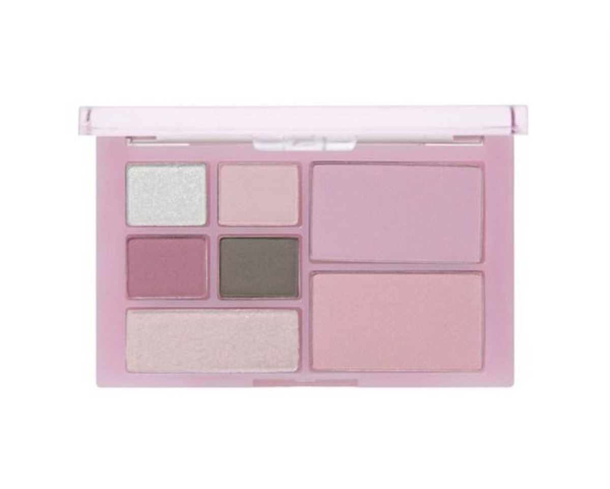 A makeup palette in a light pink compact, shown open against a plain white background. The shades include a shimmery pale green, a matte dusty pink, a deep mauve pink, a charcoal gray, a shimmery champagne, and a large matte dusty pink blush pan.