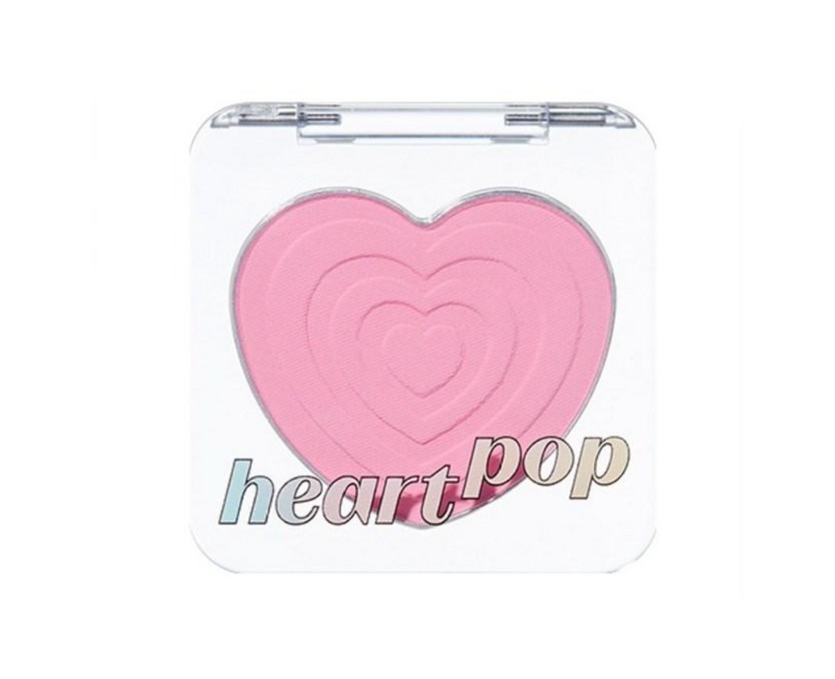 A heart-shaped pink makeup compact, likely a blush or eyeshadow, with the brand name 'heart pop' printed on the clear lid against a white background.