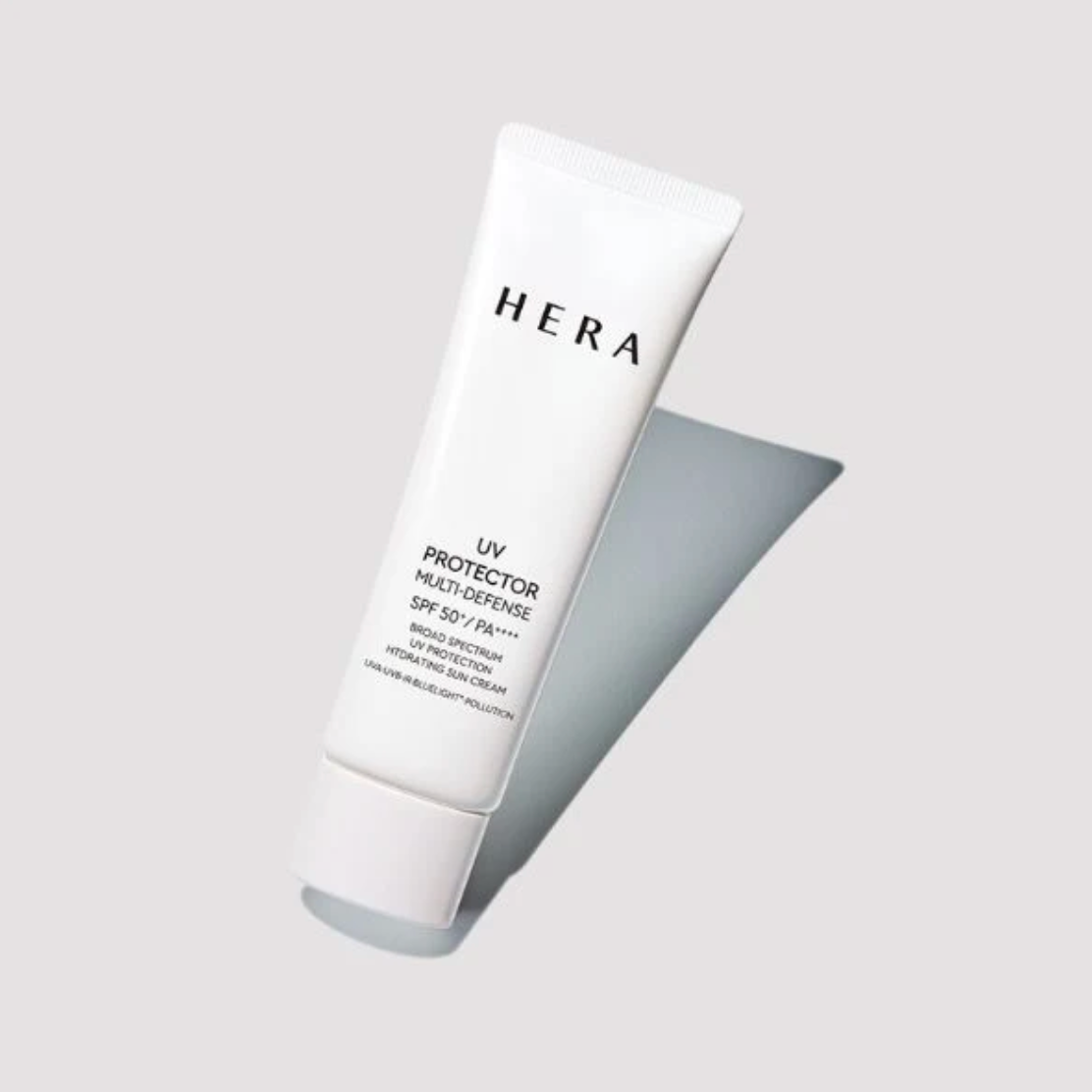 A white squeeze tube of HERA UV Protector Multi-Defense SPF 50+ PA++++ moisturizing sunscreen cream, shown at an angle on a light gray background with a soft shadow.