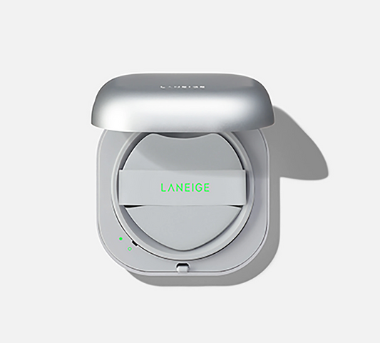 A silver Laneige compact powder case shown open from a top-down view on a light gray background. The brand name 'LANEIGE' is printed in green on the inner lid, and the outer case lid has the brand name subtly embossed near the top.