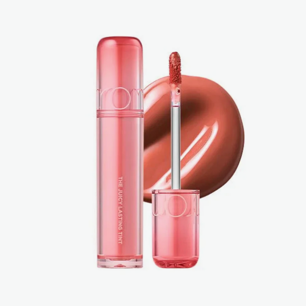 A clear pink lip gloss tube with a matching cap and applicator wand, shown alongside a glossy swatch of the nude pink formula on a light gray background.