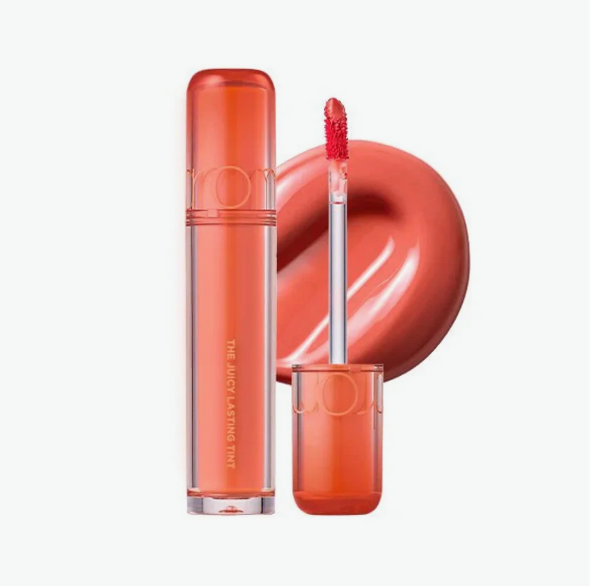 A tube of coral-pink liquid lipstick with its applicator wand shown beside it, set against a clean white background with a large color swatch behind the product.