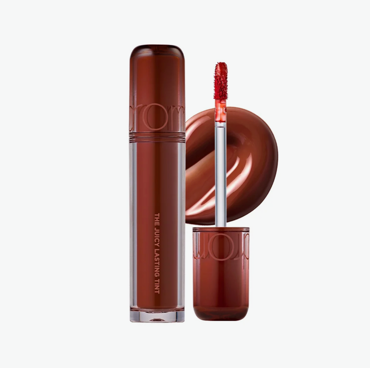 A liquid lipstick tube in a deep reddish-brown shade stands next to its cap, with the applicator showing the product color and a glossy swatch of the formula on a clean white background.