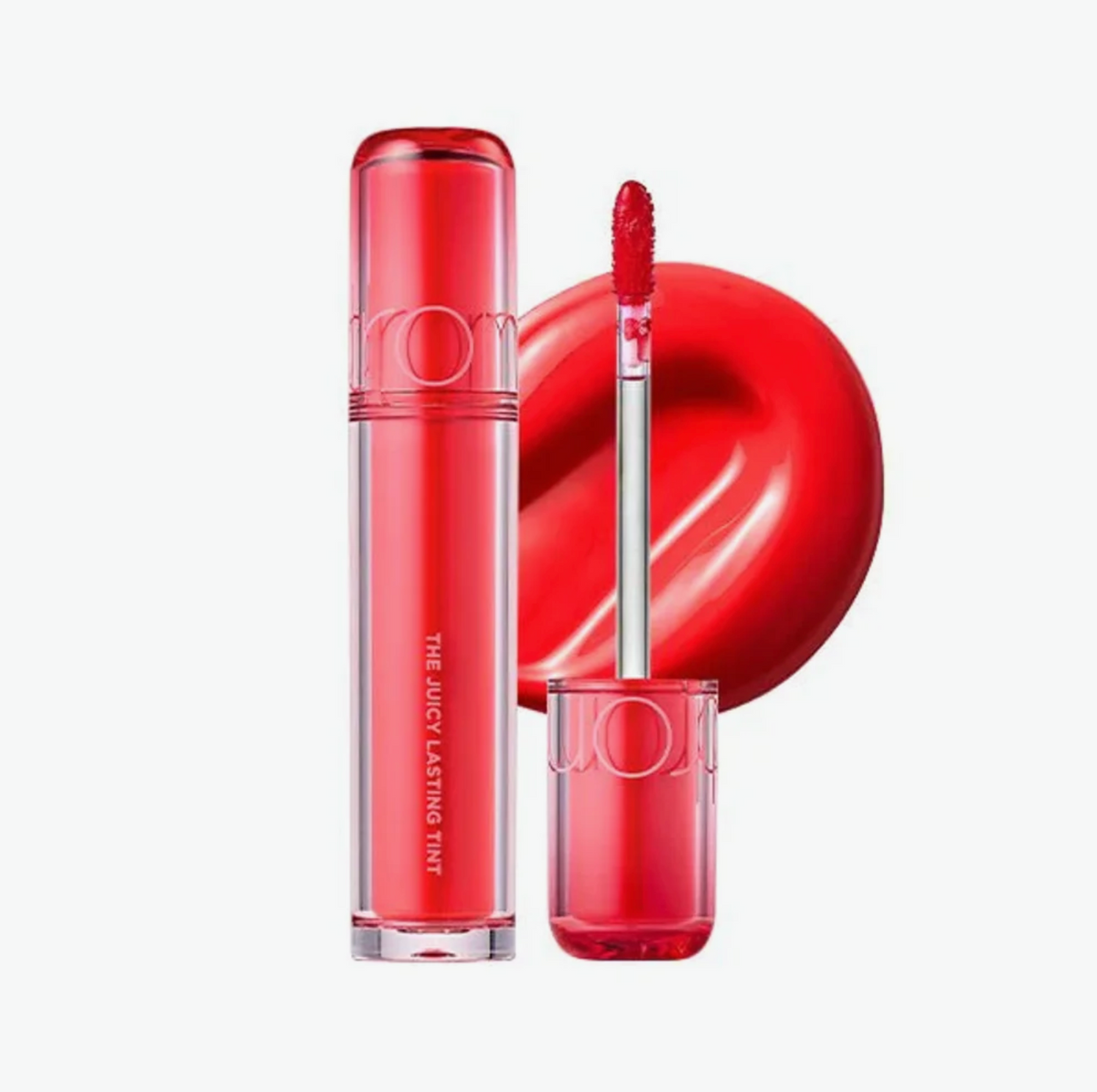 A red liquid lipstick tube and its applicator wand, with a glossy red lip swatch behind them, on a clean white background.