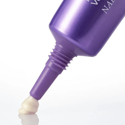 A close-up of a metallic purple cosmetic tube with a pointed applicator tip dispensing a small dollop of off-white cream, set against a clean white background.